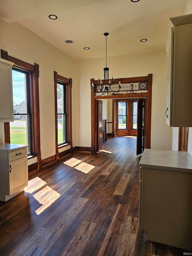 unfurnished dining area featuring french doors, a chandelier, and dark hardwood / wood-style floors