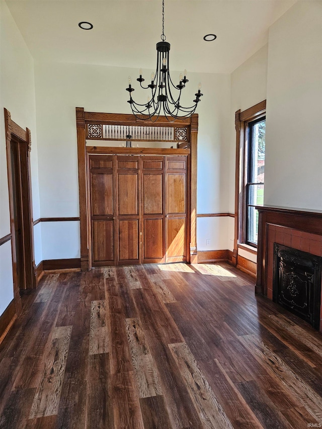 interior space with a tiled fireplace, dark hardwood / wood-style flooring, and an inviting chandelier