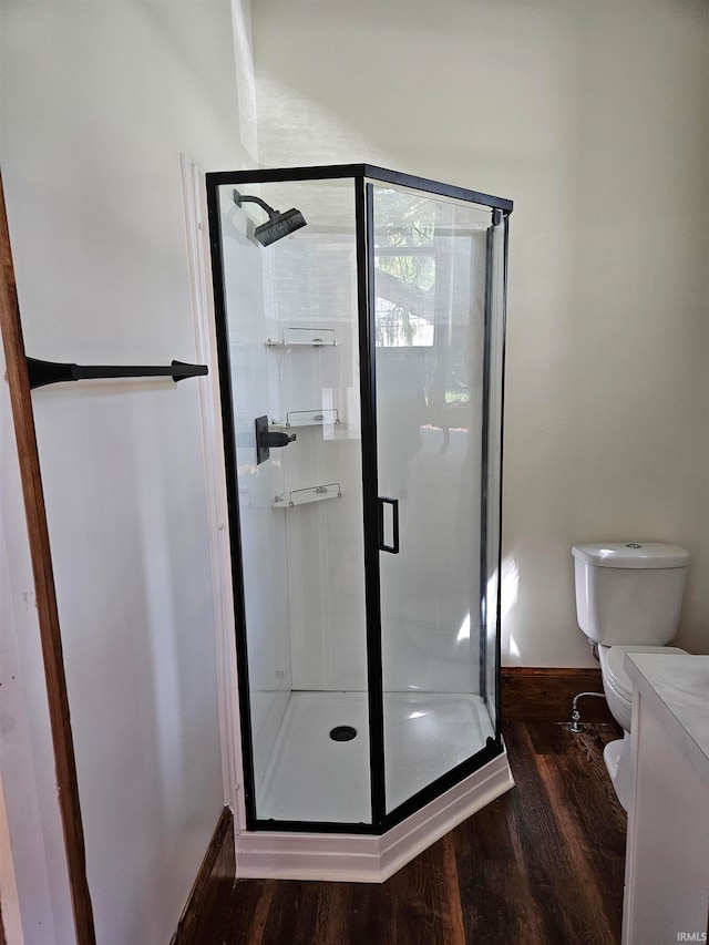 bathroom featuring wood-type flooring, toilet, and a shower with door