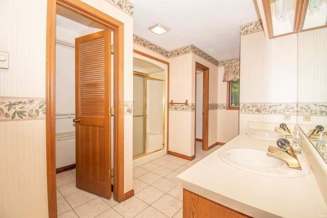 bathroom with tile patterned floors, double sink vanity, a textured ceiling, and a shower with shower door