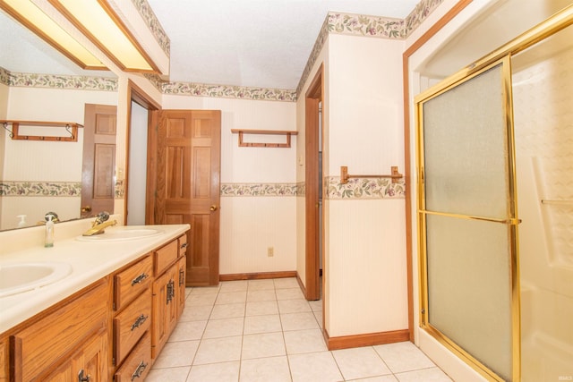 bathroom featuring tile patterned flooring, a textured ceiling, dual bowl vanity, and a shower with shower door