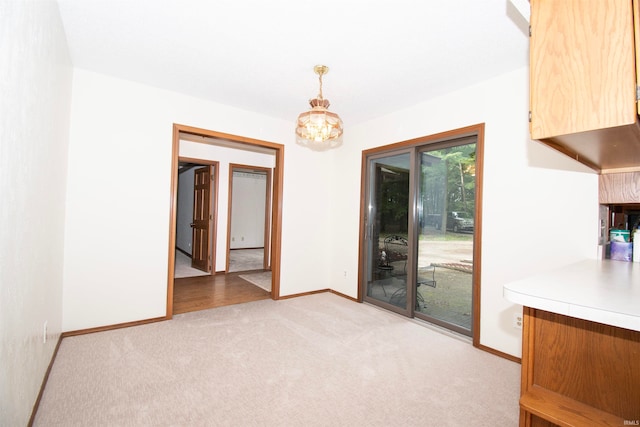 unfurnished dining area with a notable chandelier and light colored carpet