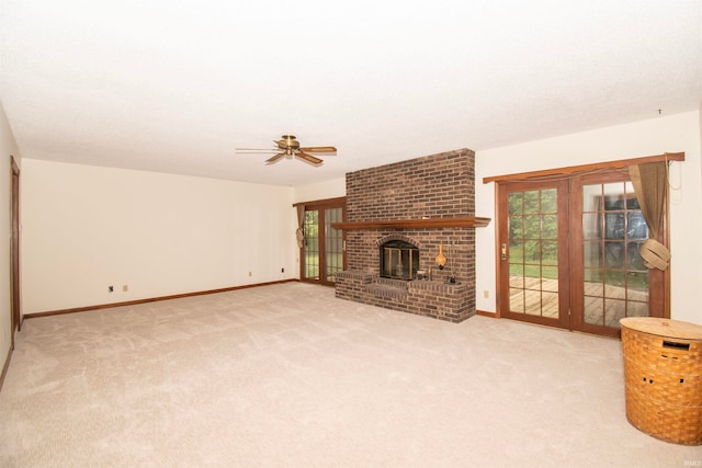 unfurnished living room with ceiling fan, light carpet, a brick fireplace, and brick wall