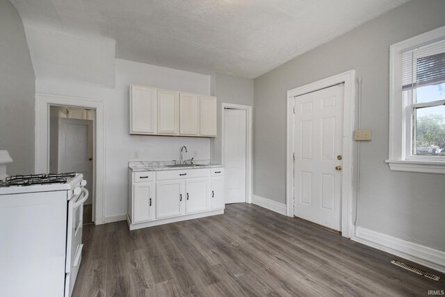 kitchen with sink, white cabinetry, range, and hardwood / wood-style floors