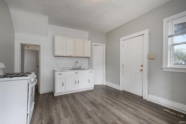 kitchen featuring sink, dark wood-type flooring, gas range gas stove, a textured ceiling, and white cabinets