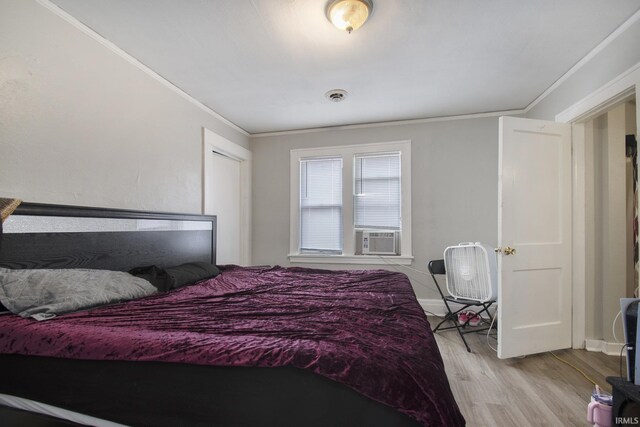 bedroom with crown molding, cooling unit, light hardwood / wood-style floors, and a closet