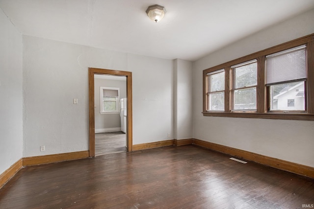 empty room featuring dark wood-type flooring and a wealth of natural light