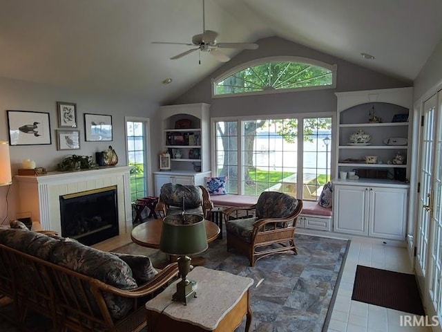 living room featuring a tile fireplace, lofted ceiling, and ceiling fan