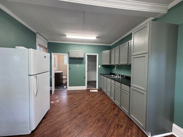 kitchen with crown molding, dark hardwood / wood-style flooring, sink, white fridge, and gray cabinetry