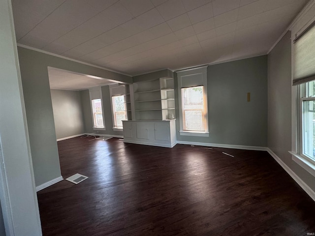 interior space with built in shelves, dark wood-type flooring, and a healthy amount of sunlight