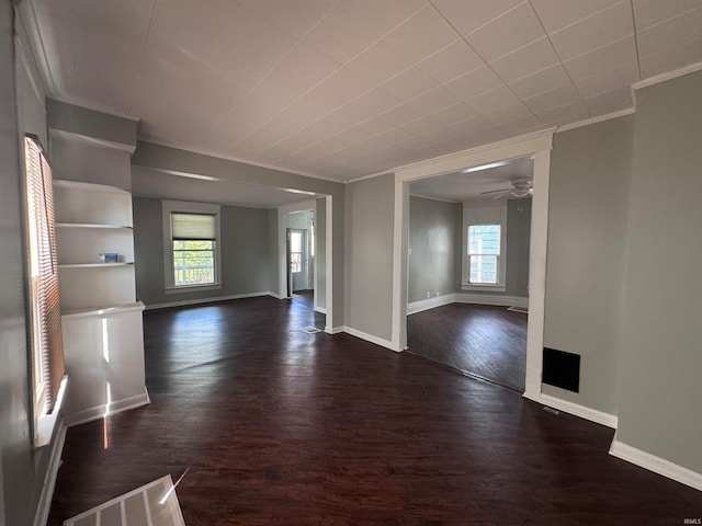 unfurnished living room with ceiling fan, dark wood-type flooring, and crown molding