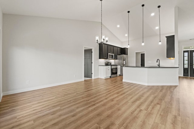 kitchen with pendant lighting, stainless steel appliances, high vaulted ceiling, and light hardwood / wood-style flooring