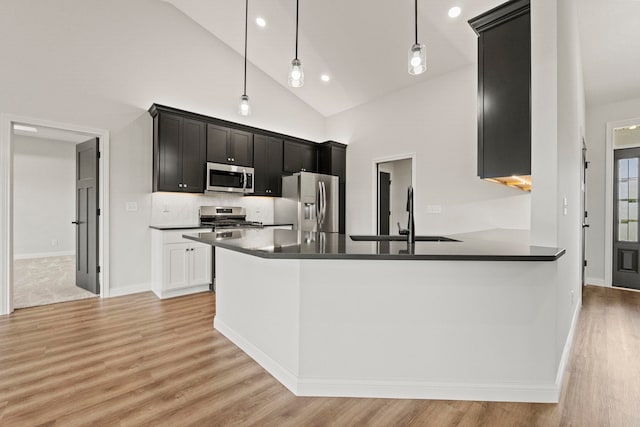 kitchen featuring decorative light fixtures, appliances with stainless steel finishes, light wood-type flooring, and sink