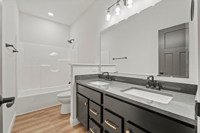 full bathroom with hardwood / wood-style flooring, bathtub / shower combination, vanity, and toilet