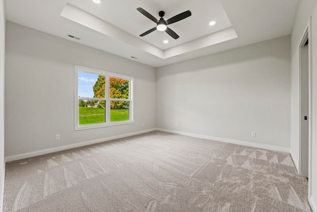 carpeted spare room with ceiling fan and a raised ceiling