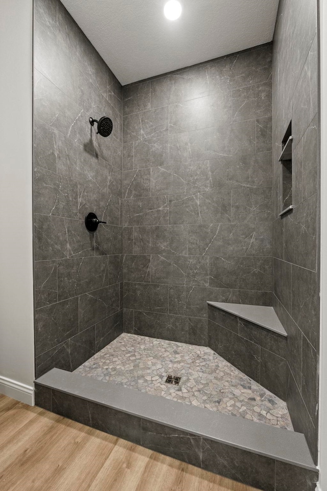 bathroom featuring hardwood / wood-style flooring and a tile shower