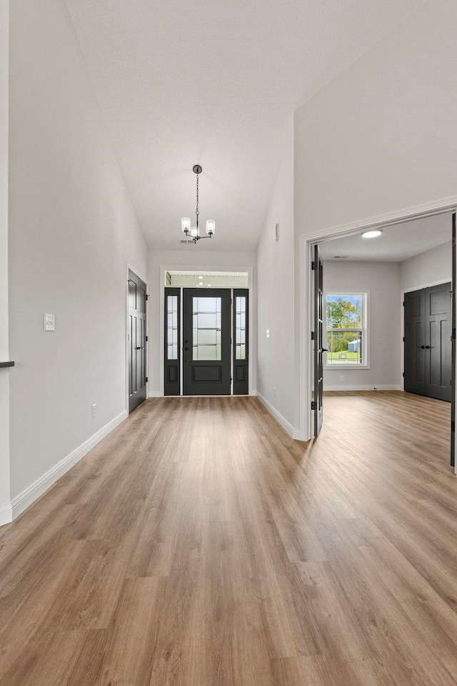 foyer entrance with an inviting chandelier, light hardwood / wood-style floors, and high vaulted ceiling