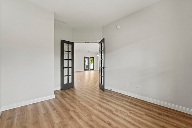 unfurnished room featuring french doors and light hardwood / wood-style floors