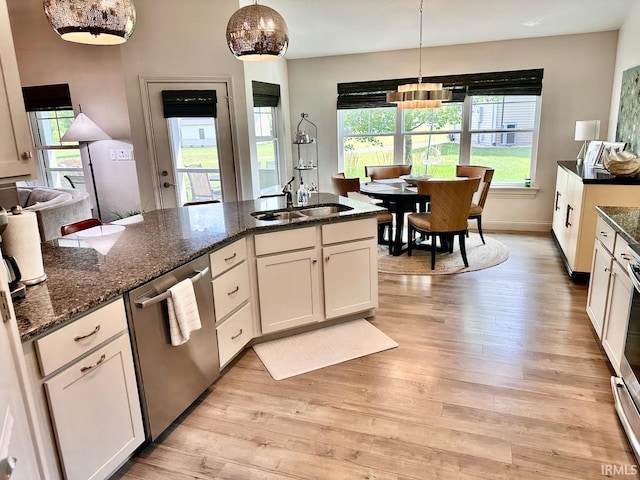 kitchen featuring light hardwood / wood-style flooring, stainless steel dishwasher, dark stone counters, and white cabinetry