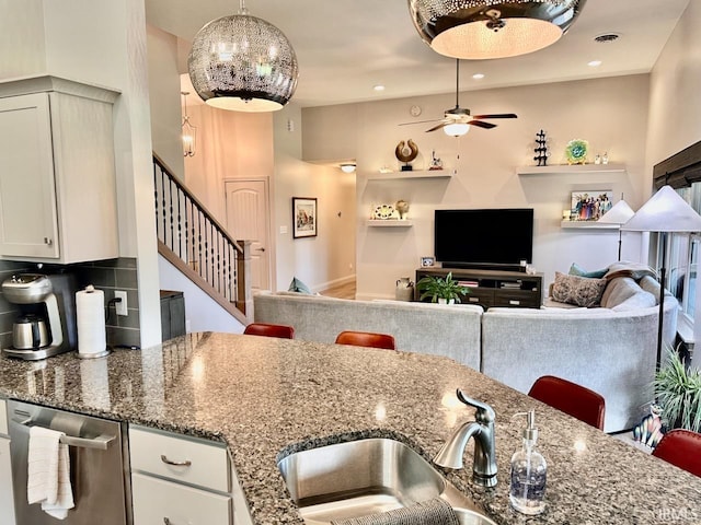 kitchen with stainless steel dishwasher, stone counters, white cabinets, ceiling fan, and decorative backsplash