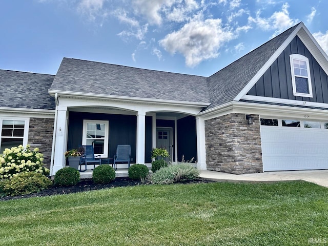 view of front of home with a garage, covered porch, and a front lawn