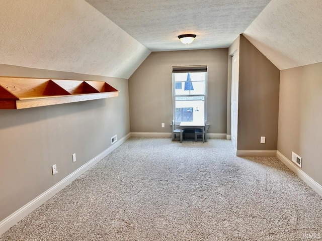 bonus room featuring lofted ceiling, carpet flooring, and a textured ceiling