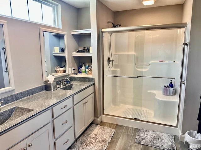 bathroom featuring a shower with shower door, dual vanity, and hardwood / wood-style floors