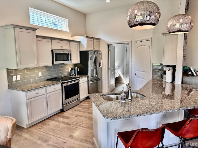 kitchen with stainless steel appliances, hanging light fixtures, tasteful backsplash, light hardwood / wood-style flooring, and kitchen peninsula