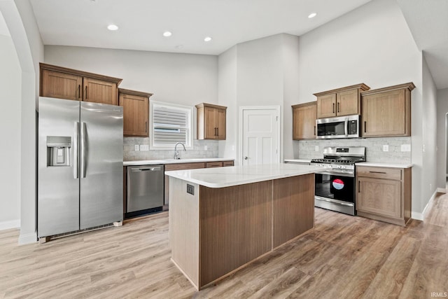 kitchen featuring a center island, stainless steel appliances, light countertops, light wood-style floors, and a sink