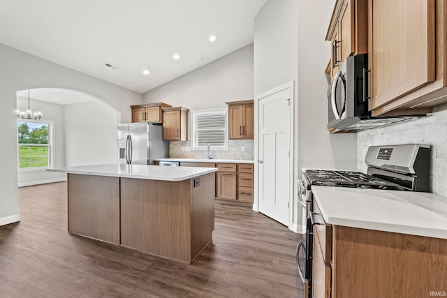 kitchen with visible vents, dark wood-style flooring, a center island, stainless steel appliances, and a sink