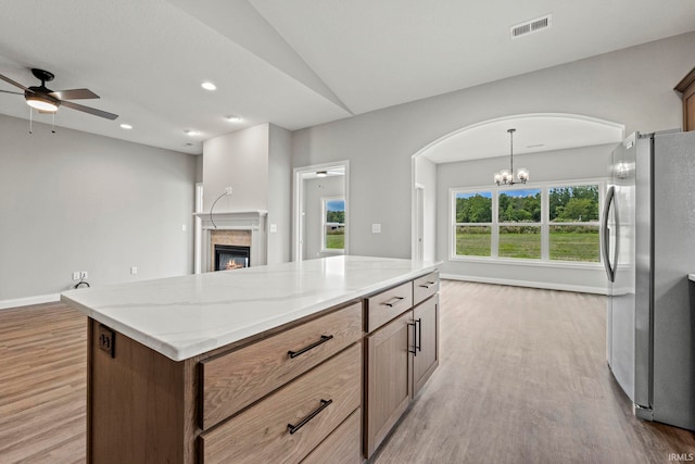 kitchen featuring light stone counters, a glass covered fireplace, freestanding refrigerator, and light wood-style floors