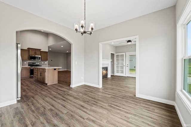 kitchen featuring open floor plan, light countertops, appliances with stainless steel finishes, and a glass covered fireplace