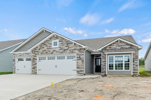 craftsman house with a shingled roof, concrete driveway, stone siding, and an attached garage