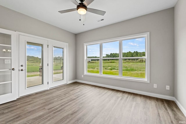 interior space with baseboards, visible vents, ceiling fan, and wood finished floors