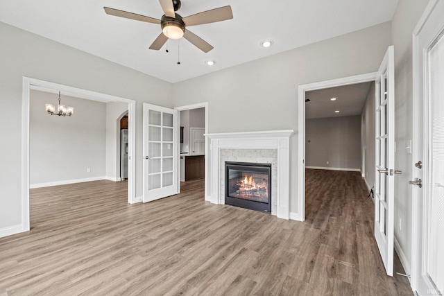 unfurnished living room with light wood-type flooring, a glass covered fireplace, and baseboards