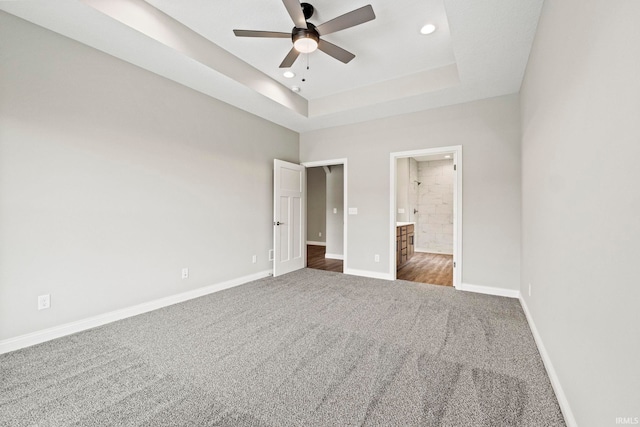 unfurnished bedroom featuring carpet floors, a tray ceiling, baseboards, and recessed lighting