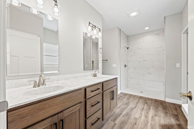 full bath featuring tiled shower, a sink, and wood finished floors