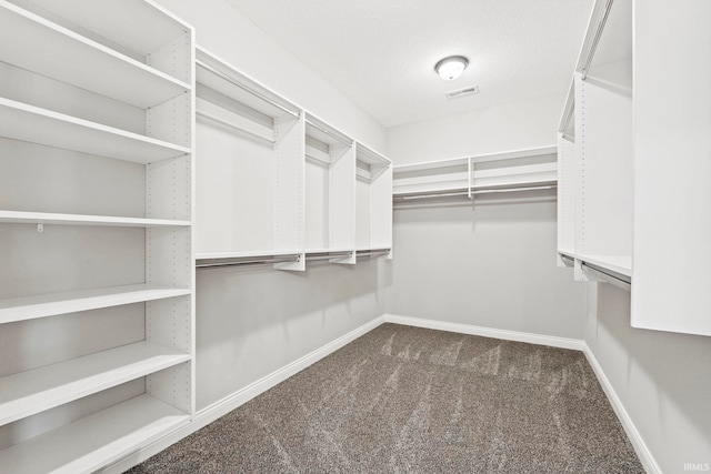 spacious closet with dark carpet and visible vents