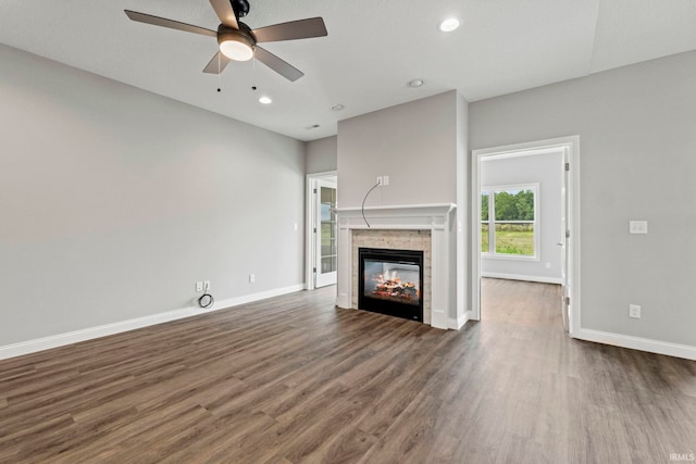 unfurnished living room featuring baseboards, a ceiling fan, wood finished floors, a stone fireplace, and recessed lighting