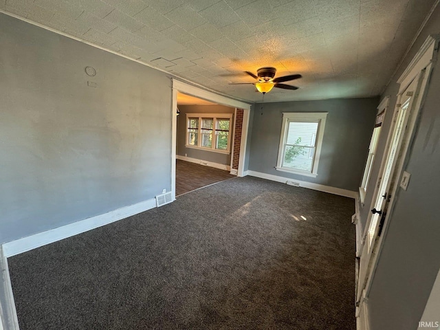 spare room featuring ceiling fan and dark colored carpet