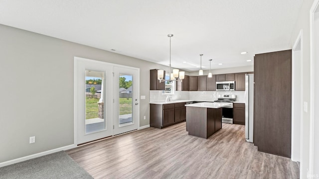 kitchen featuring a kitchen island, decorative light fixtures, decorative backsplash, stainless steel appliances, and dark brown cabinets