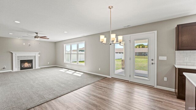 interior space with ceiling fan with notable chandelier and light hardwood / wood-style floors