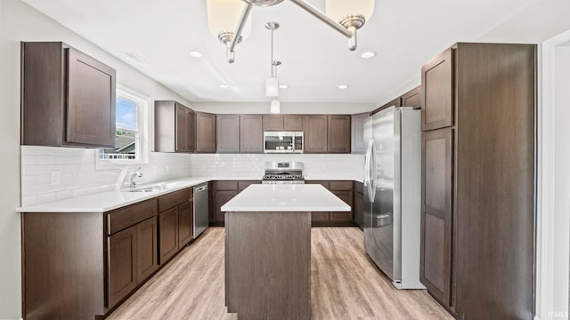 kitchen featuring stainless steel appliances, a kitchen island, dark brown cabinetry, and light hardwood / wood-style flooring