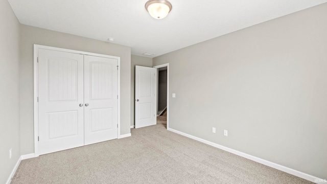 unfurnished bedroom featuring light carpet and a closet