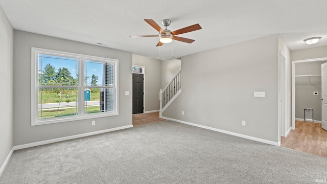 unfurnished room with a textured ceiling, carpet floors, and ceiling fan