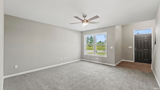 carpeted empty room with ceiling fan and a textured ceiling