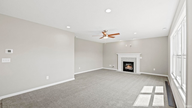 unfurnished living room with ceiling fan, carpet floors, and a brick fireplace