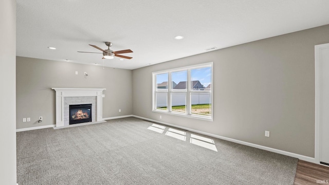 unfurnished living room featuring ceiling fan, a fireplace, and carpet