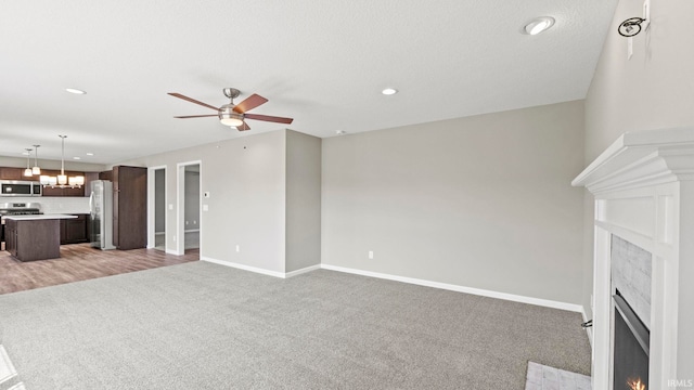 unfurnished living room featuring light carpet and ceiling fan with notable chandelier