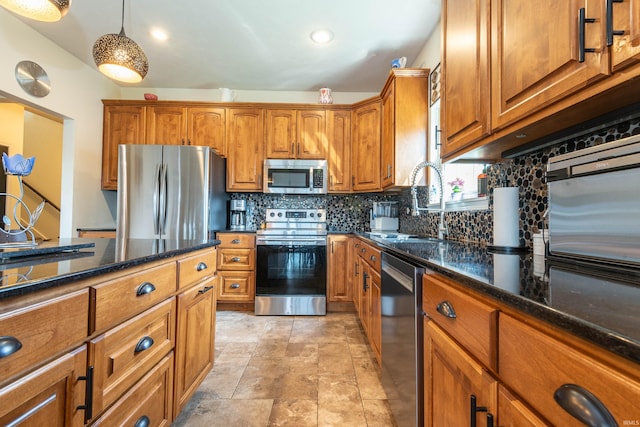 kitchen featuring sink, dark stone countertops, decorative backsplash, hanging light fixtures, and stainless steel appliances